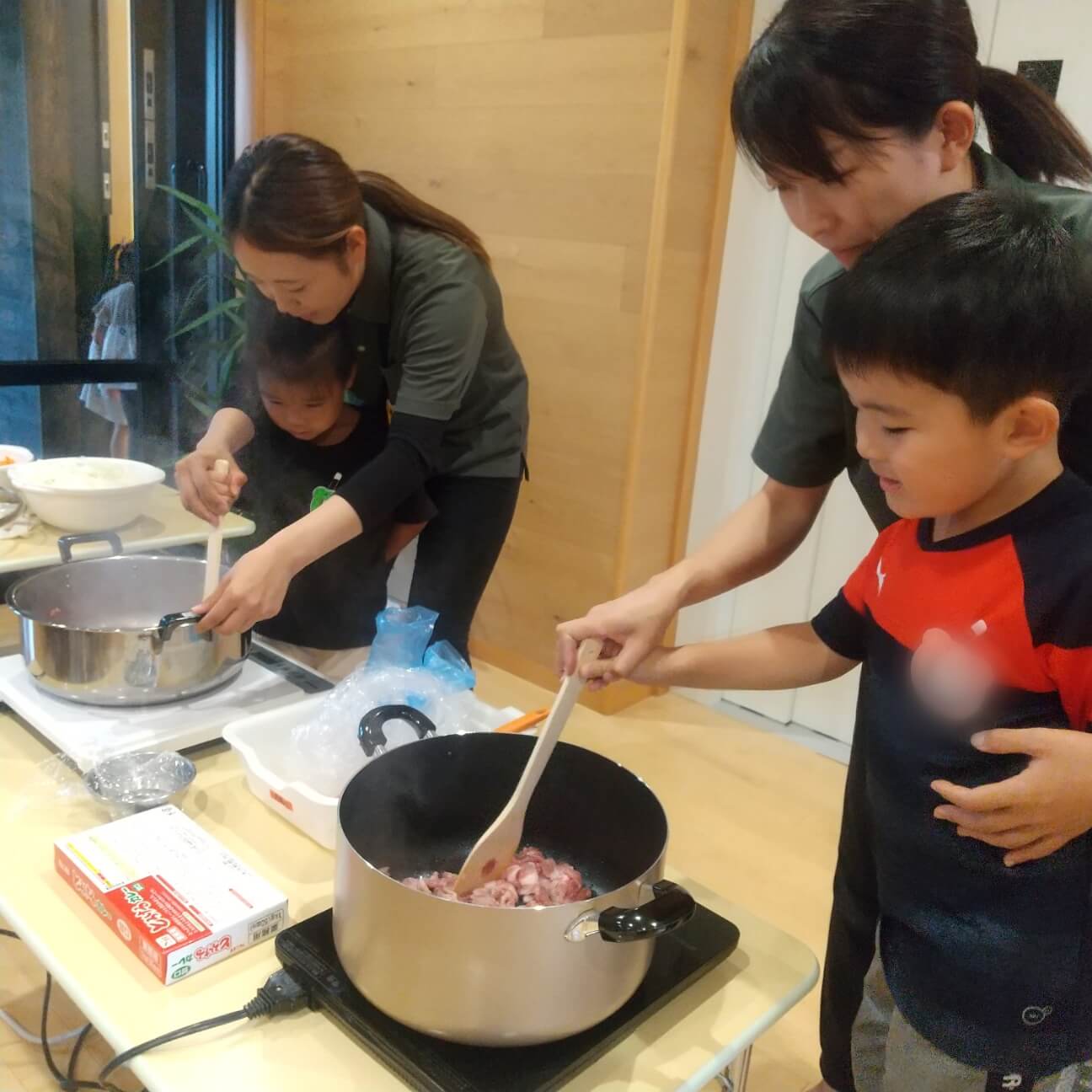 鍋で具材を炒める子どもたち