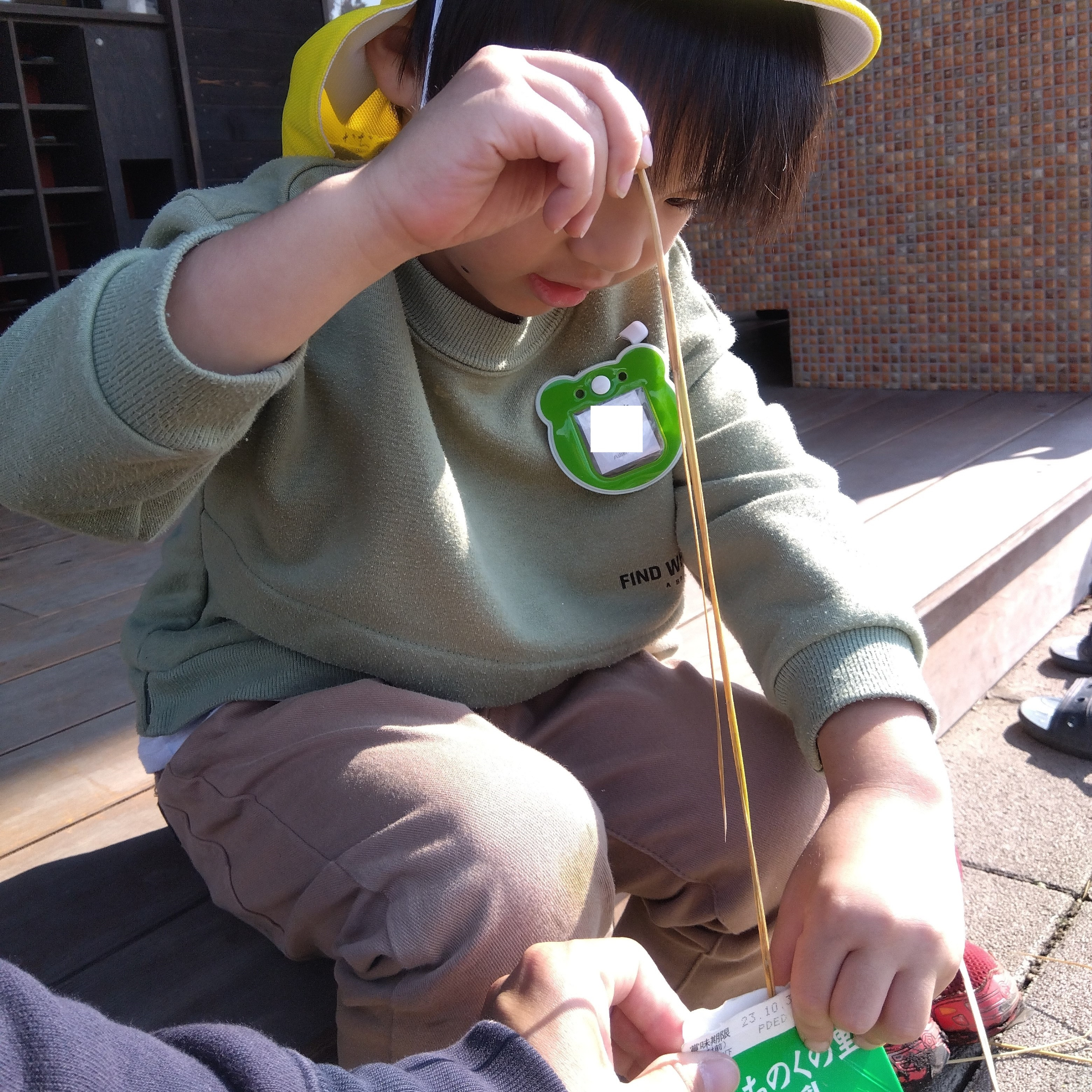 スタッフと脱穀する子ども