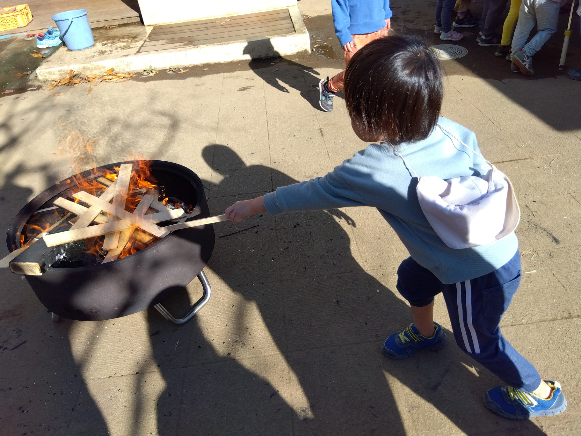 焚火に薪をくべる子ども