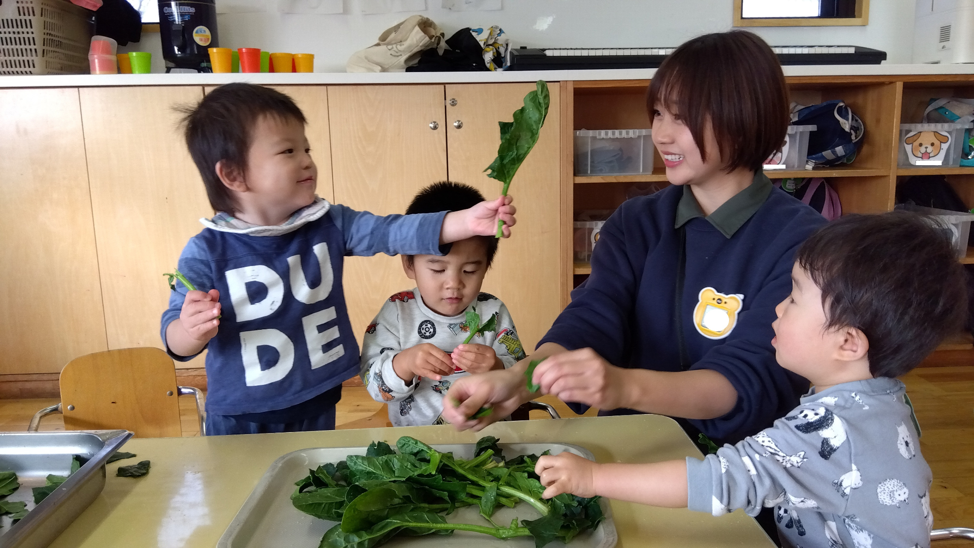 ほうれん草の葉を掲げる子ども