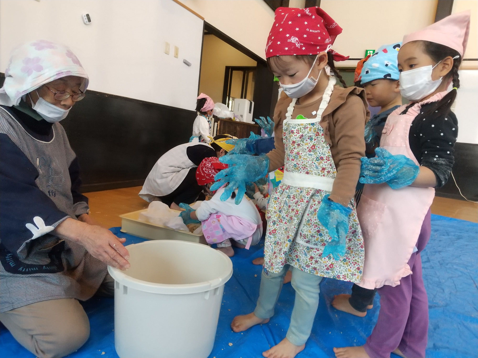 丸めた大豆をバケツに投げ入れる子どもたち