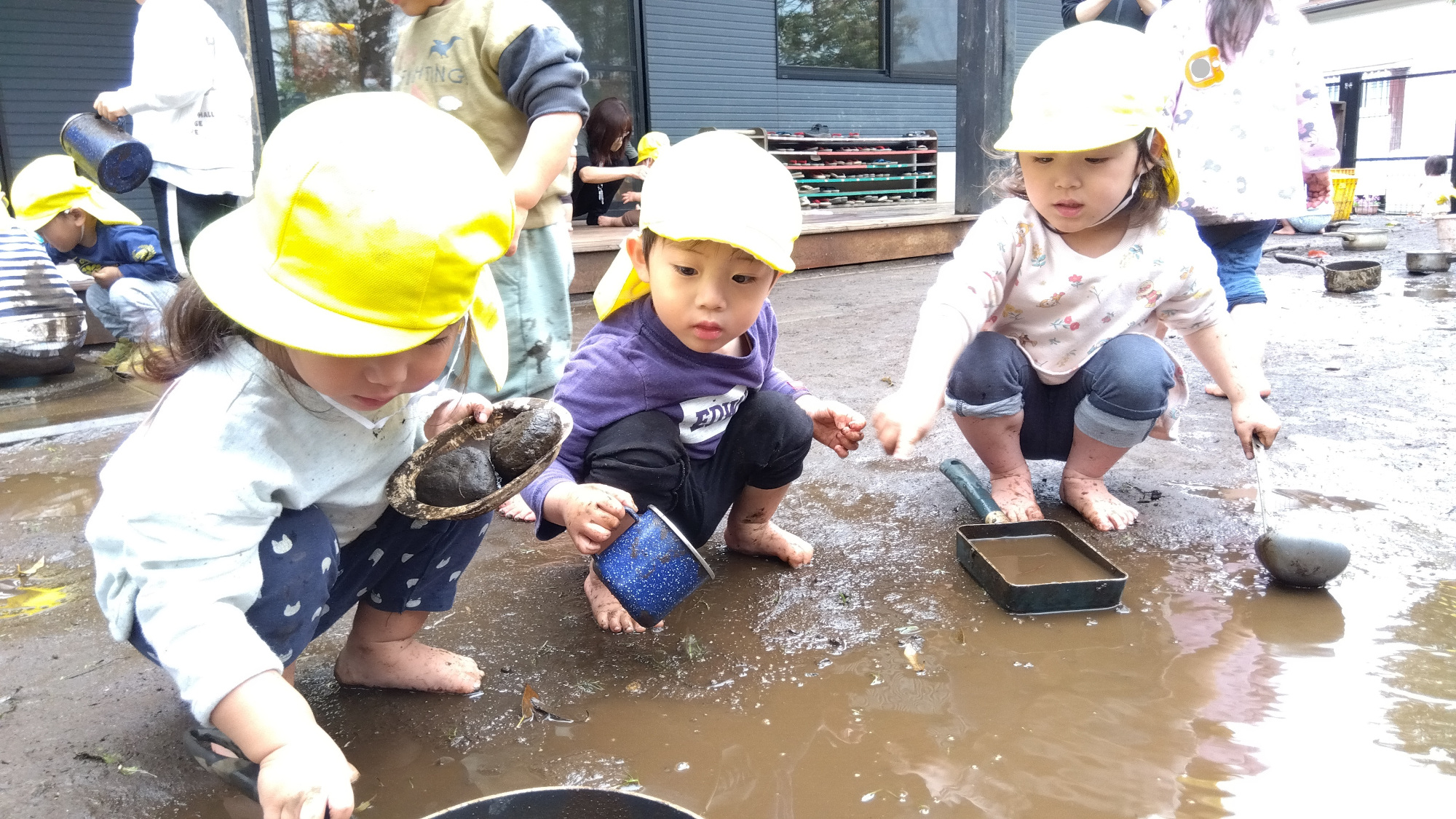園庭で泥遊びをする子どもたち