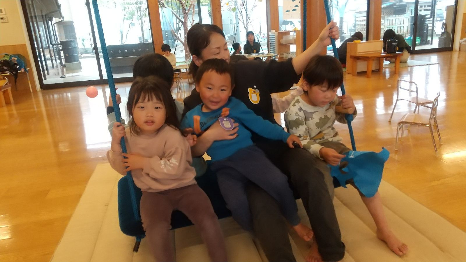 スタッフと一緒にブランコに乗る子どもたち
