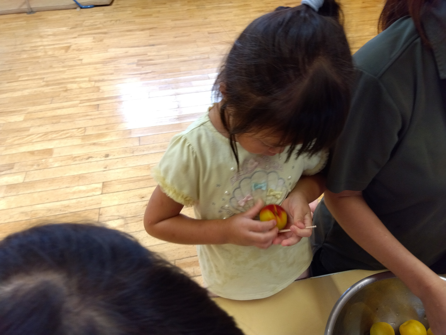 つまようじで梅の実のヘタを取る子どもたち
