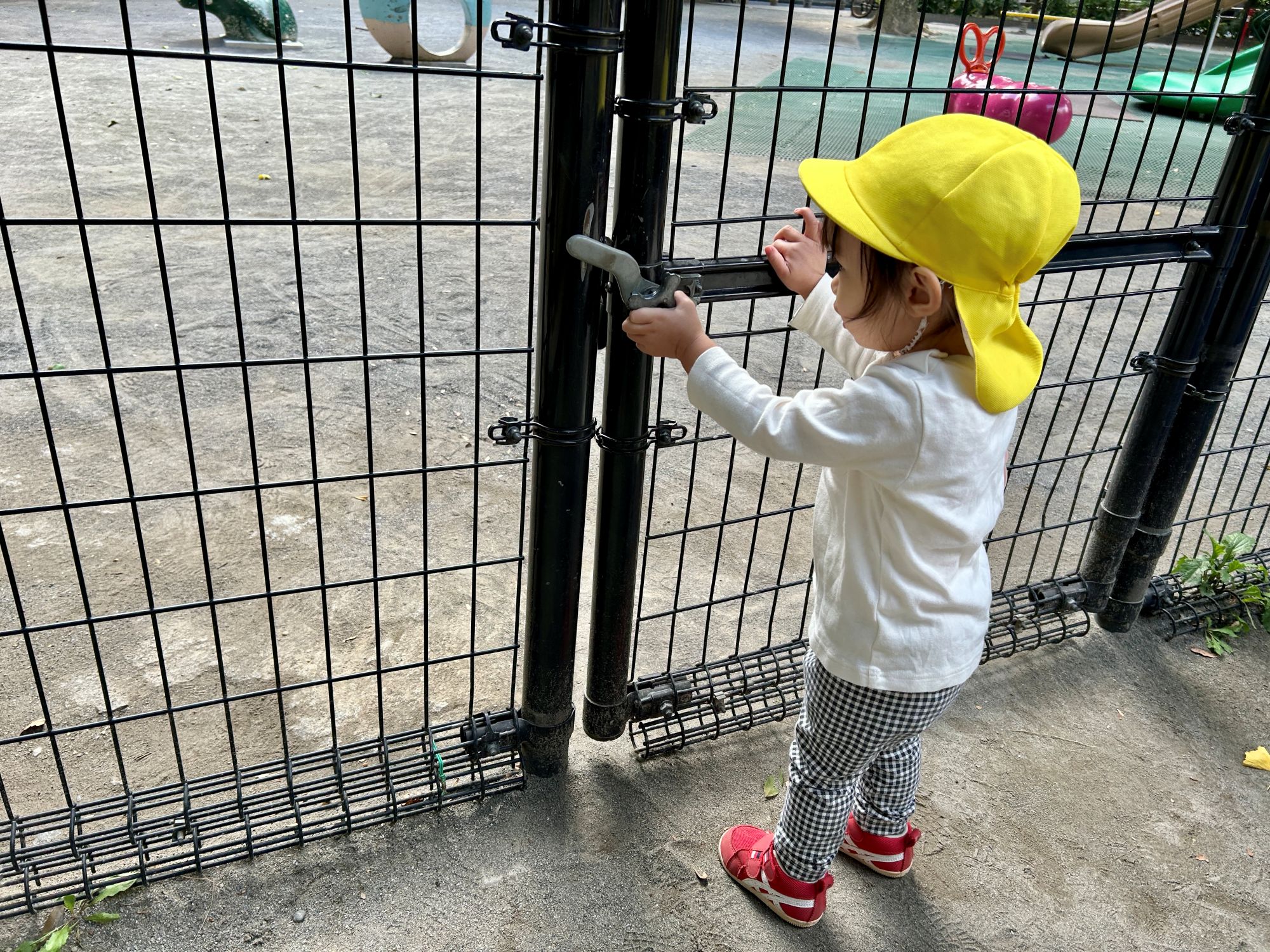 砂場出入口のドアの金具を触る園児