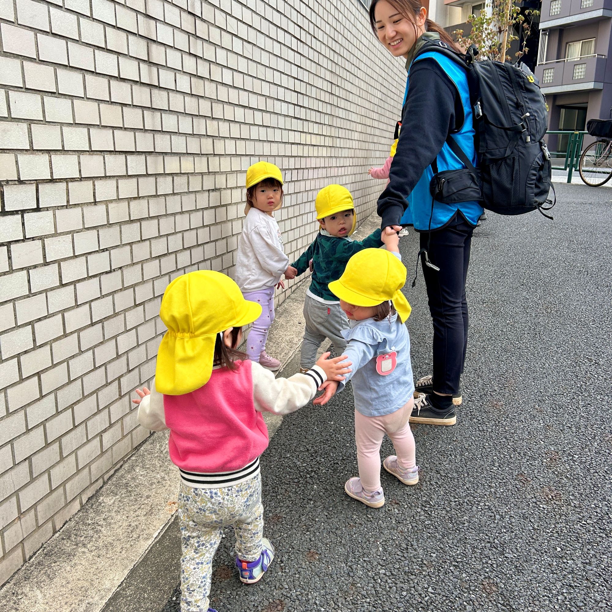 散歩の帰り道、友だちに手をつなごうと誘う園児