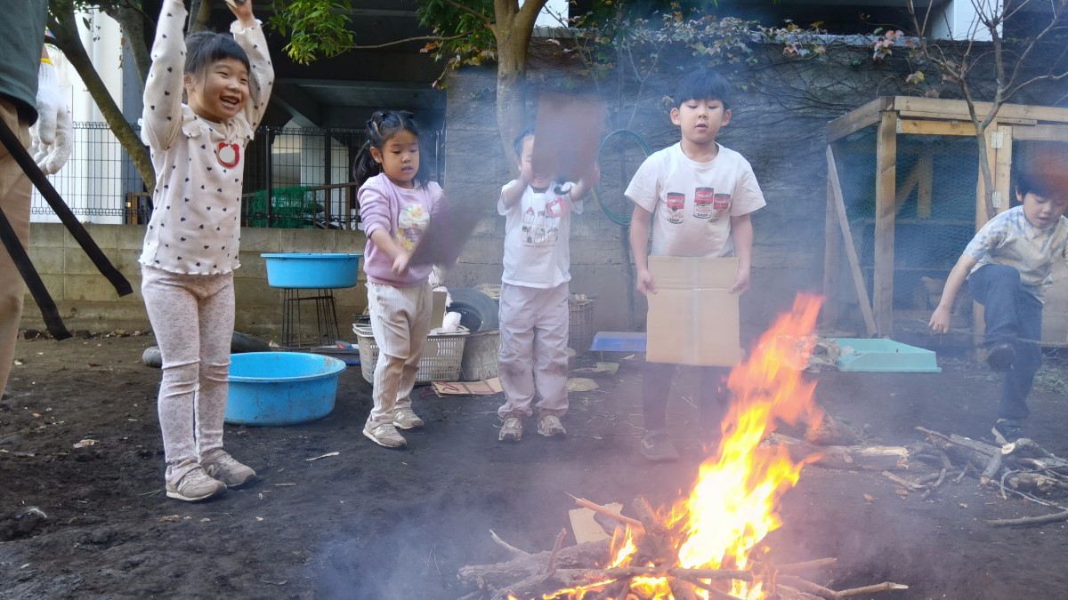 段ボールで焚き火をあおぐ子ども