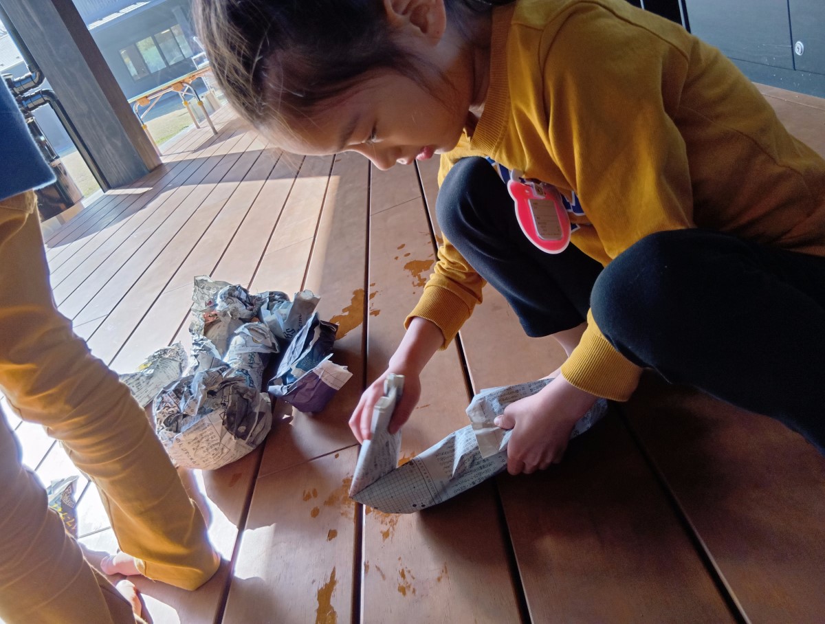 さつまいもを新聞紙で包む子ども