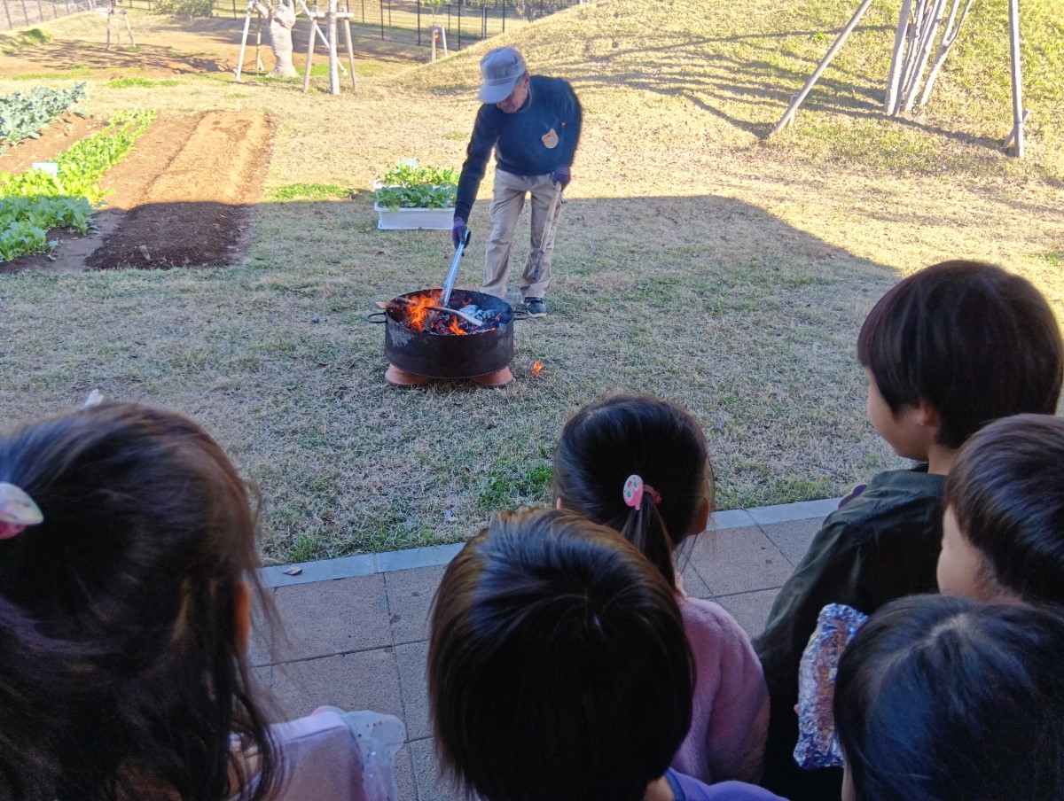 焚き火を遠巻きに見守る子どもたち