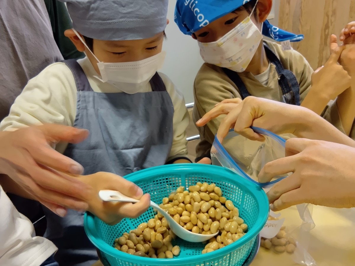 大豆をスプーンでビニール袋に移す子ども