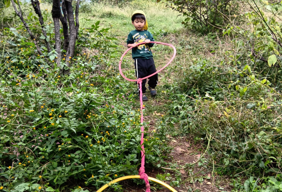 紐を付けたフープを引っ張る子ども