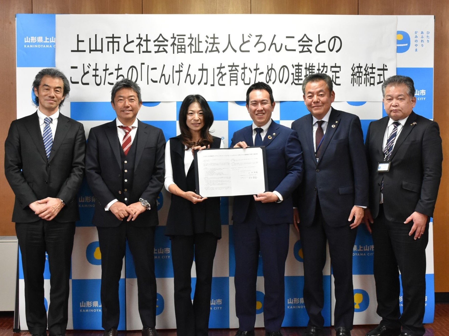 締結式で、協定書を手に安永理事長と上山市長が締結書を手に記念撮影に臨む様子