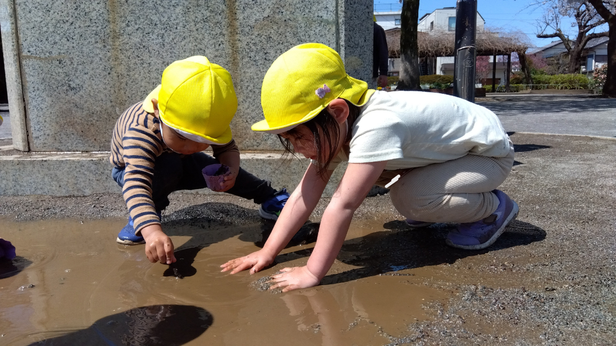 水たまりに触れる子どもたち