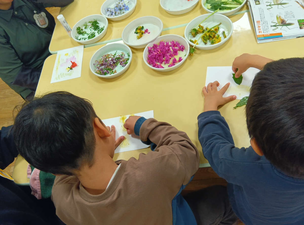 花や草を紙にこすって色をつけるようす