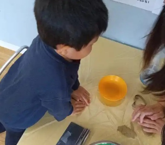 粘土を押しつぶす子どもたち