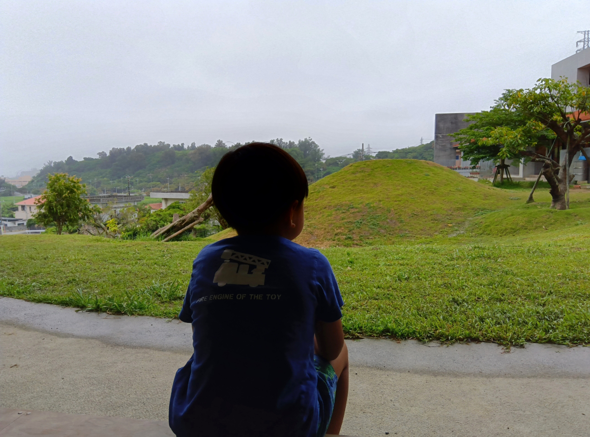 縁側から外を眺める子どもの背中