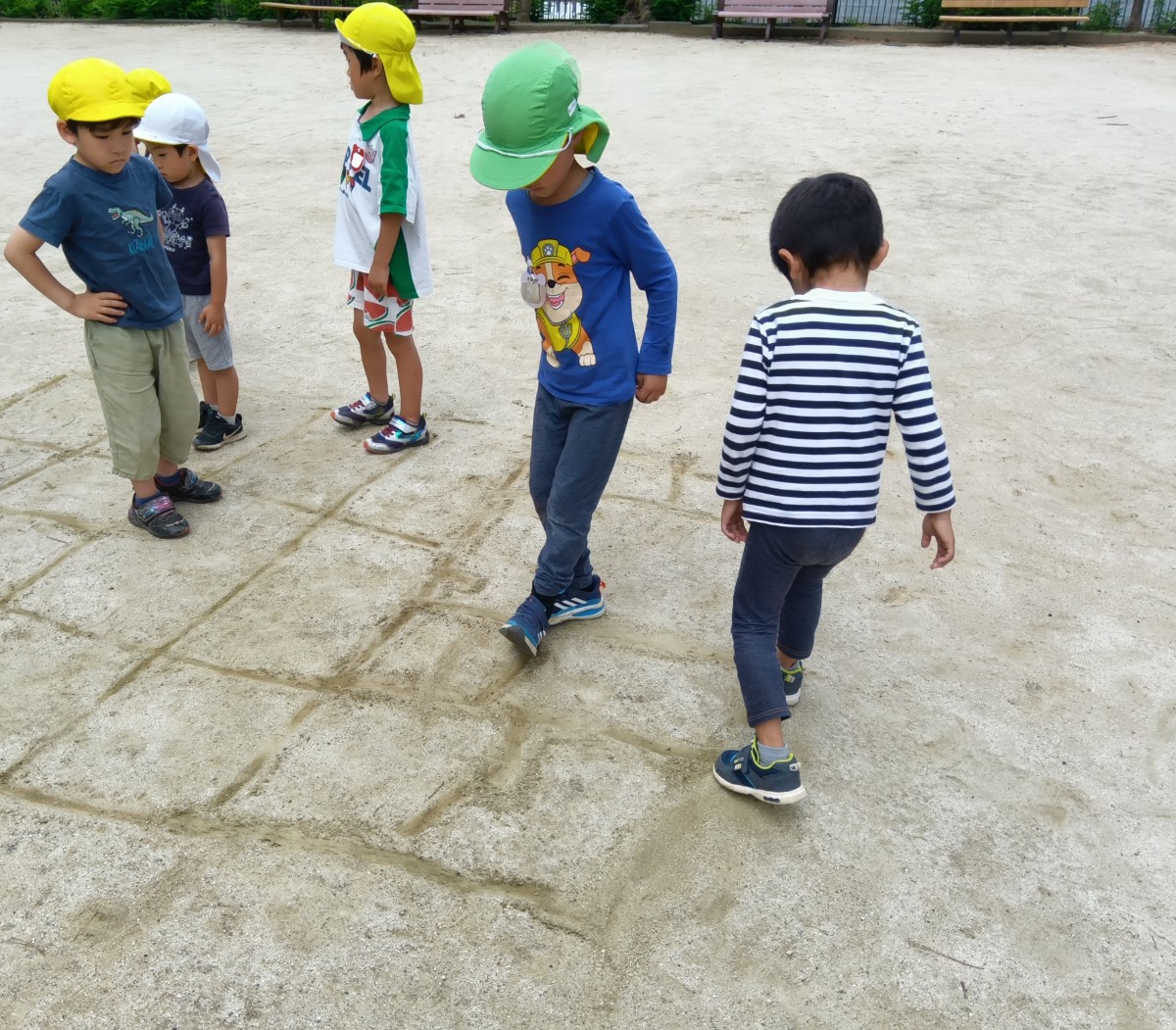 地面にマスを描いて鬼ごっこをする子どもたち