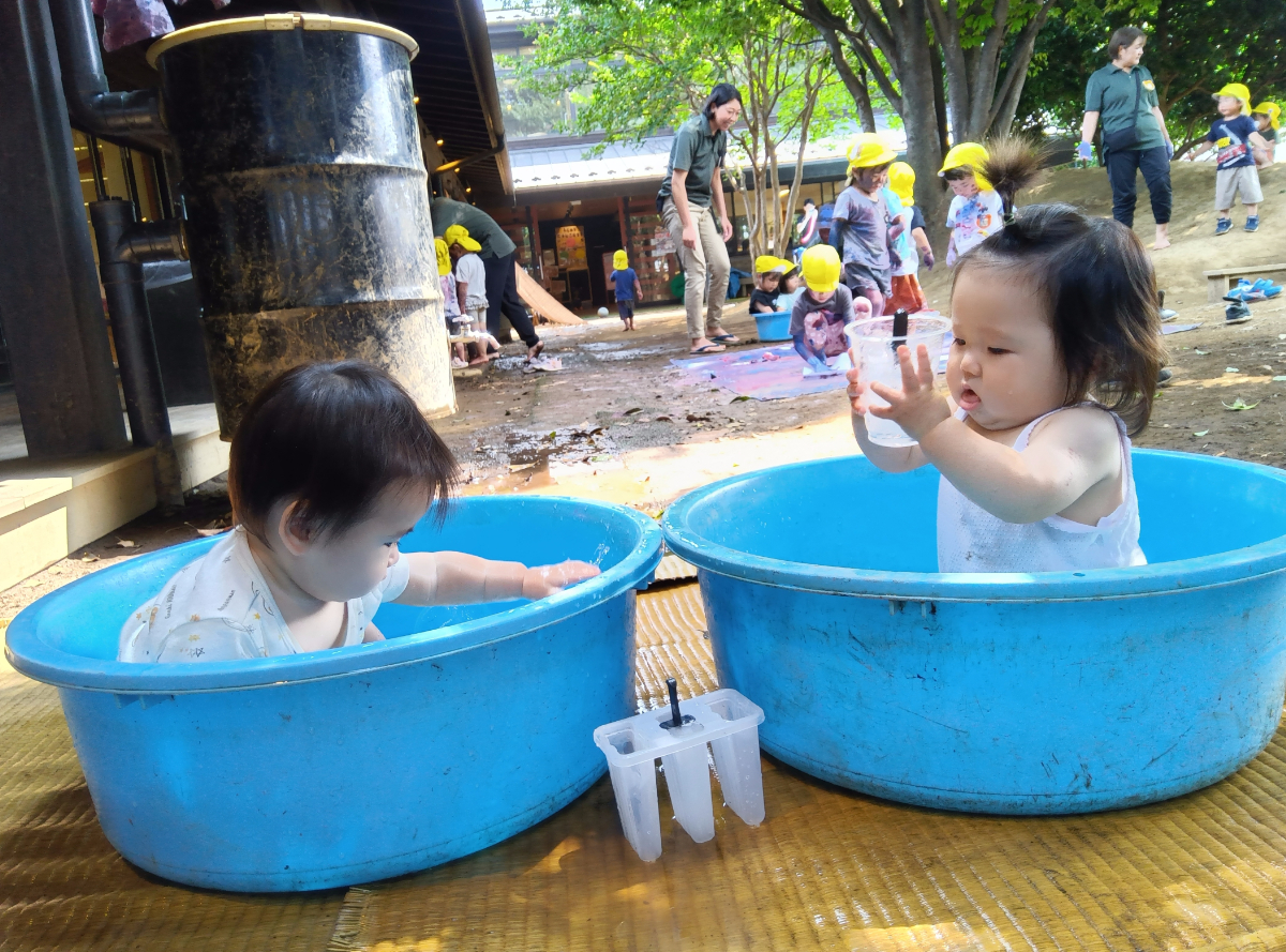 たらいで水遊びをする子どもたち