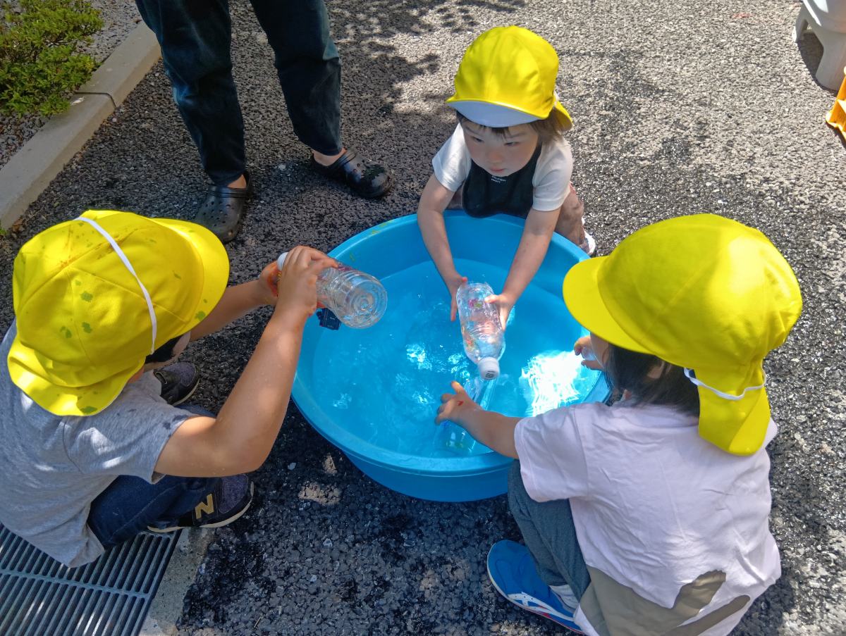たらいの色水を囲む子どもたち