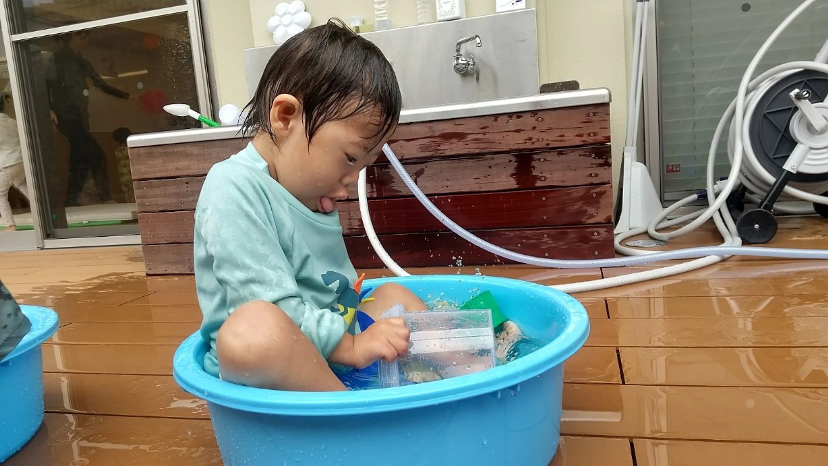 タライに入って水遊びする子ども