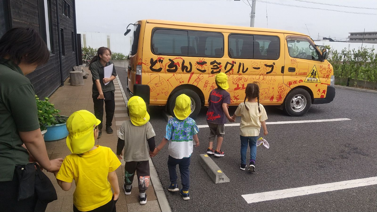 駐車場にあるどろんこバスを見つめる子どもたち