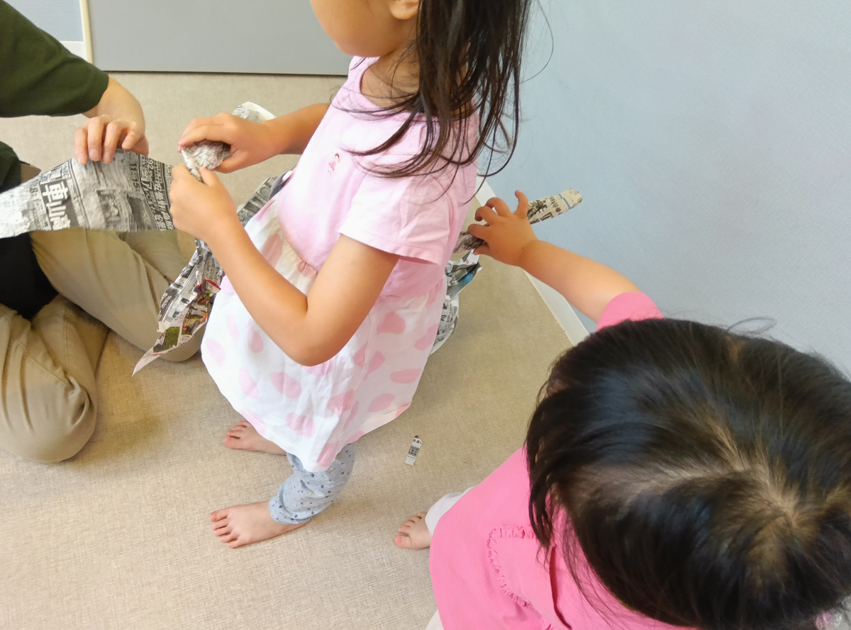 新聞紙を使って友だちと楽しむ様子