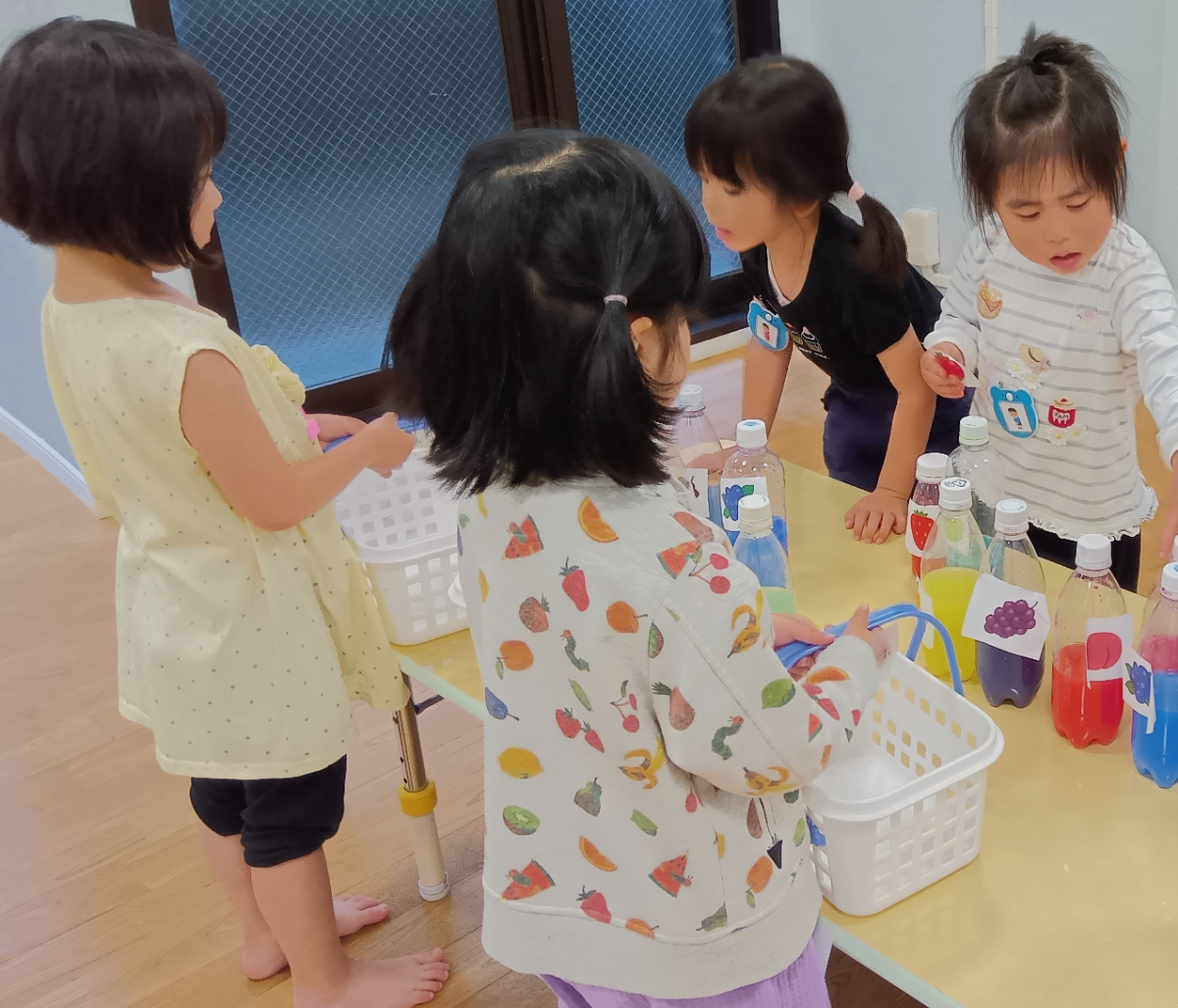 色水でジュース屋さんごっこをする子どもたち