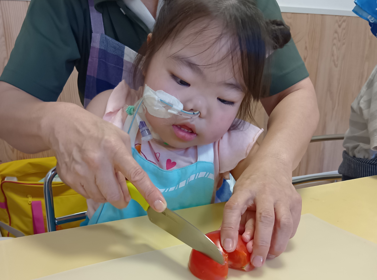 包丁でトマトを切る子ども