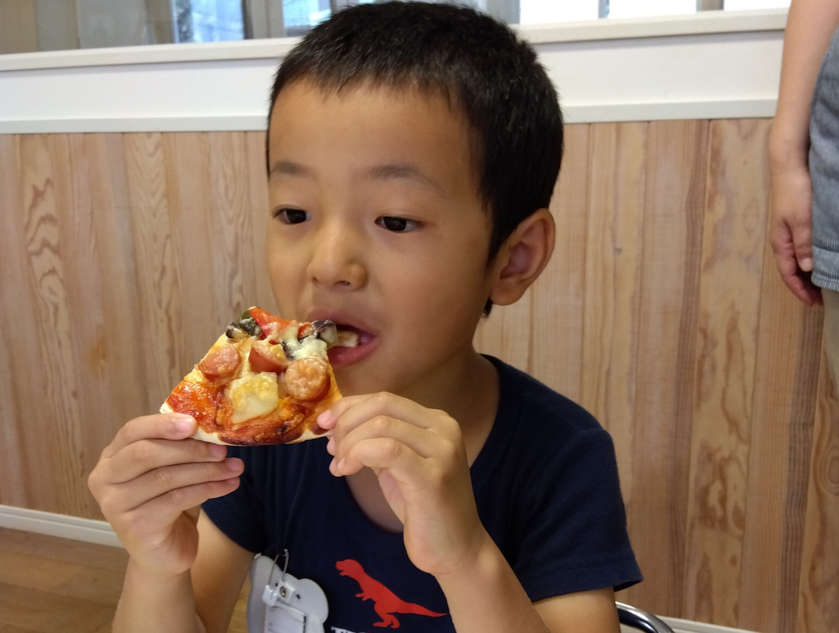 焼きあがったピザを食べる子ども