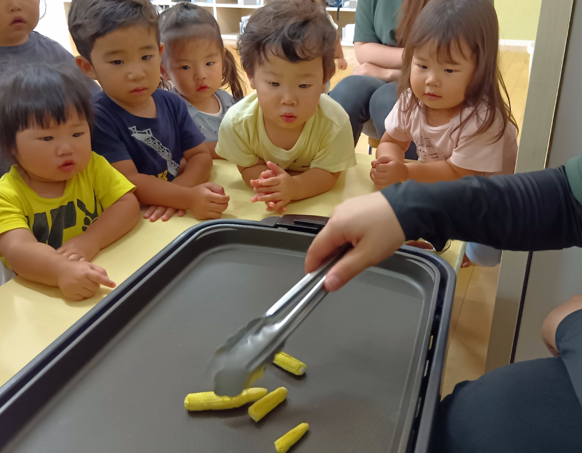 ヤングコーンを焼く様子を見つめる子どもたち