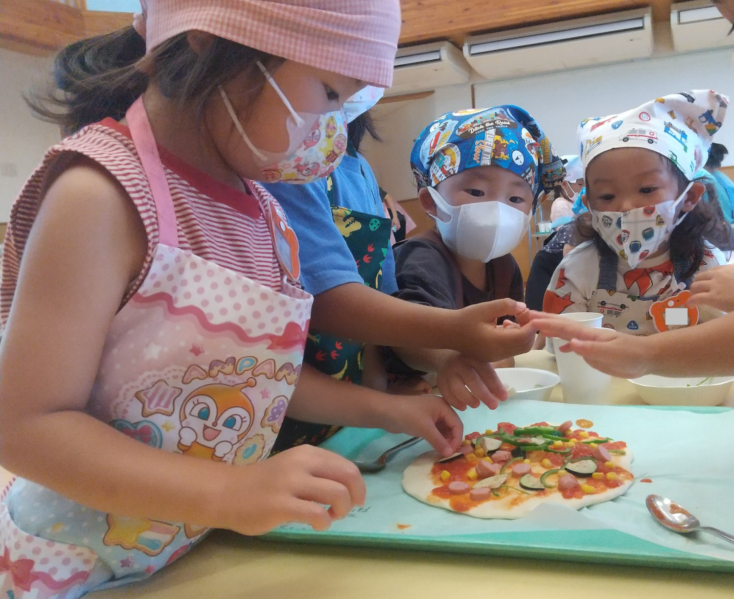 夏野菜を生地にのせる子どもたち