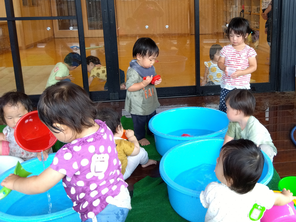 たらいで水遊びをする子どもたち