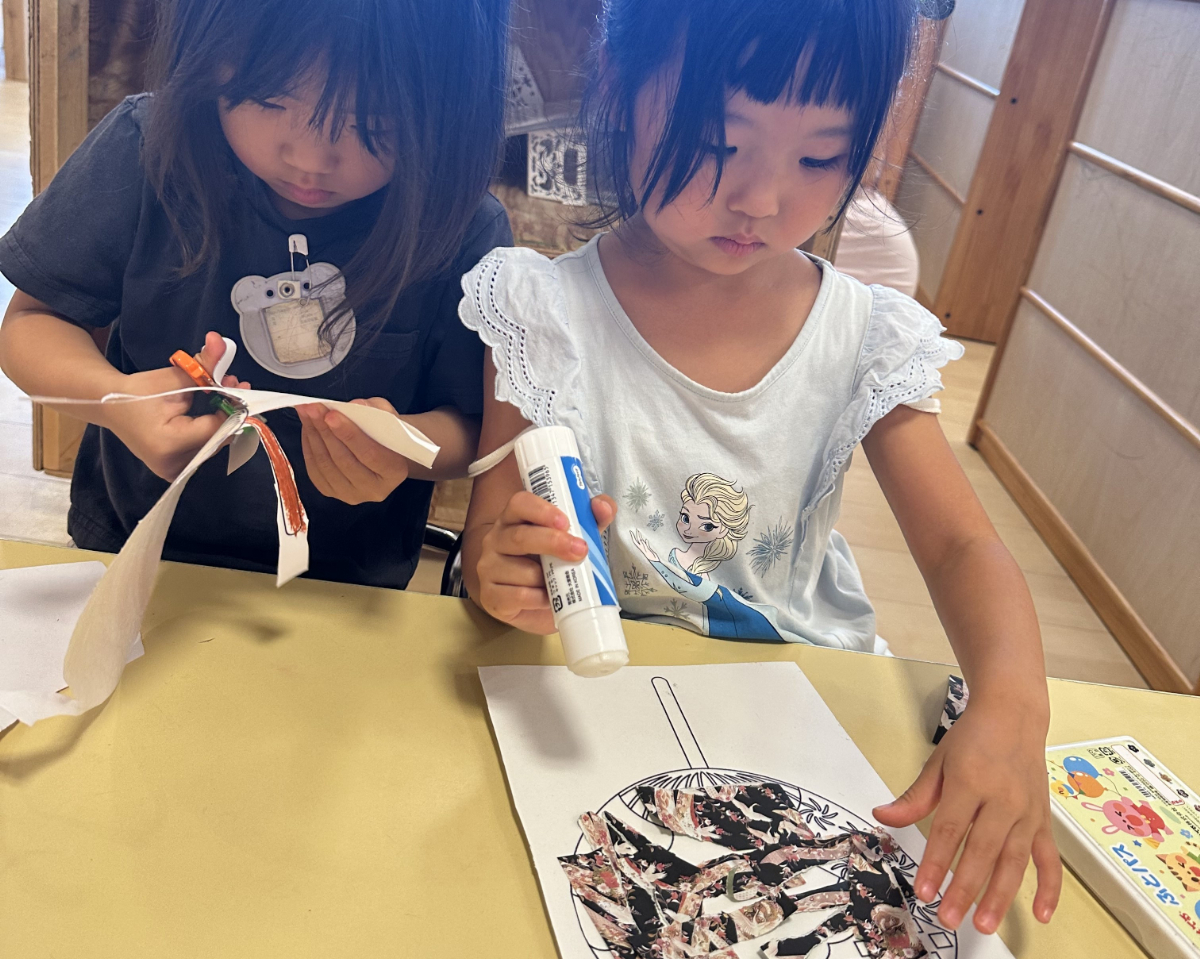 うちわに千代紙を貼る子ども