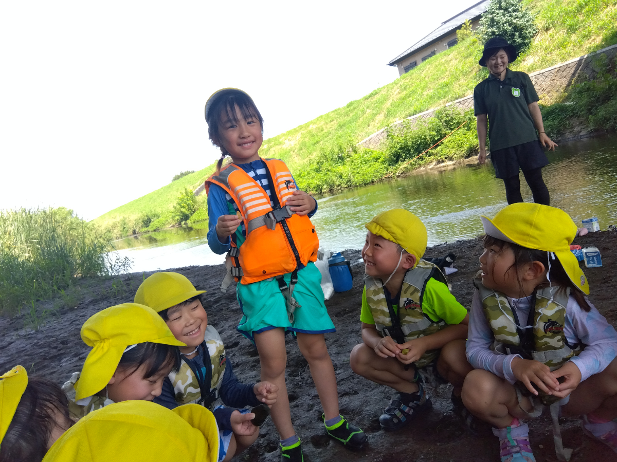輪になって選んだ石に名前をつける子どもたち