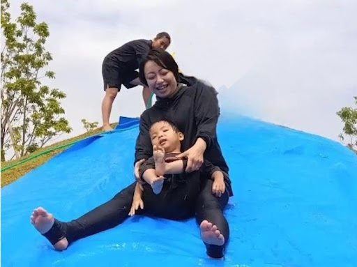 スタッフとウォータースライダーを楽しむ子ども