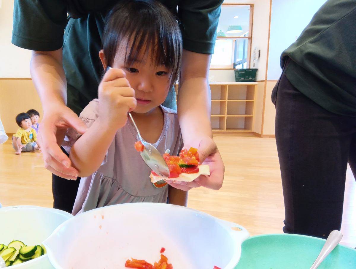 ピザ生地に具材を乗せる子ども