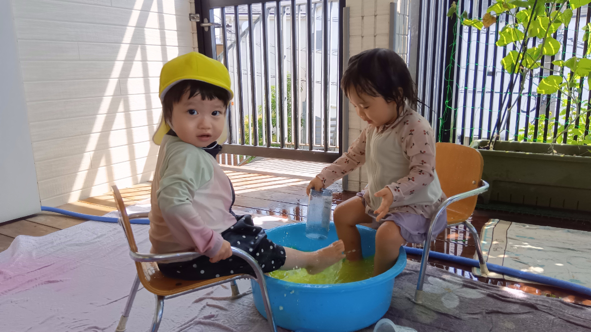 水を入れたたらいに足を入れて遊ぶ子どもたち