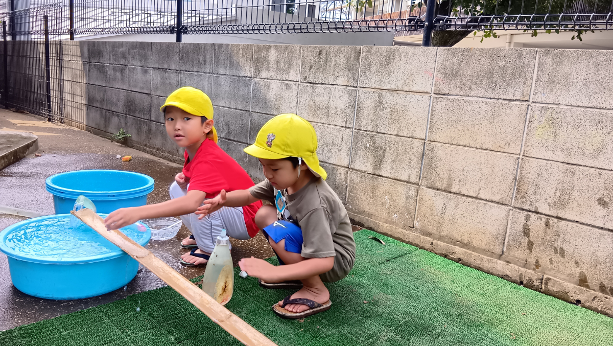 竹の水路で水遊びする子どもたち