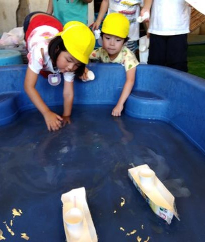 牛乳パックの船を浮かべる子どもたち