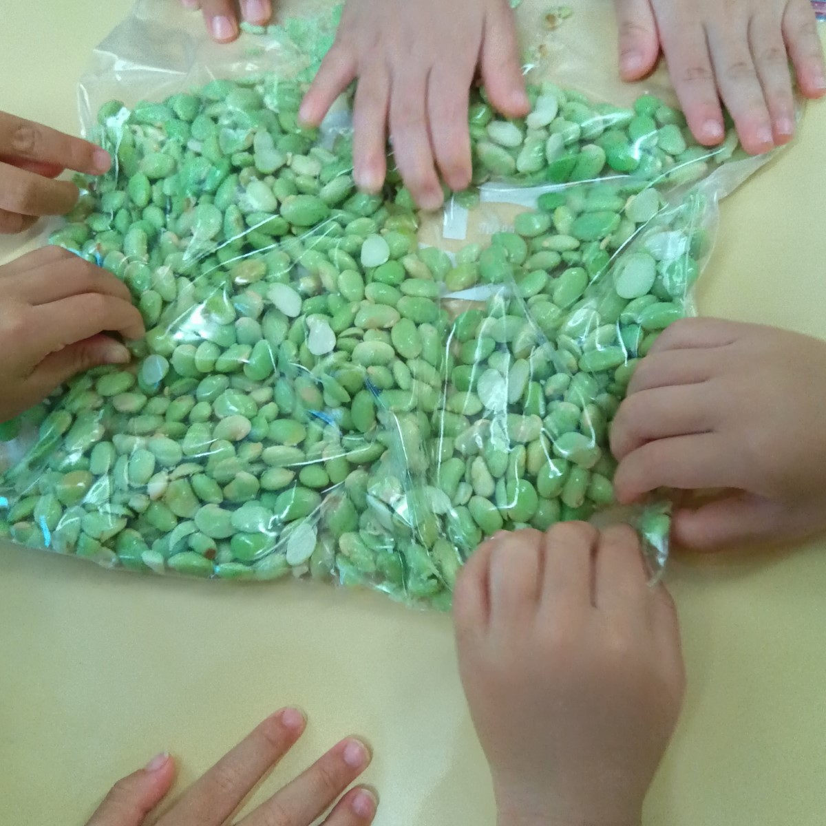 袋に入れた枝豆を手で潰す様子