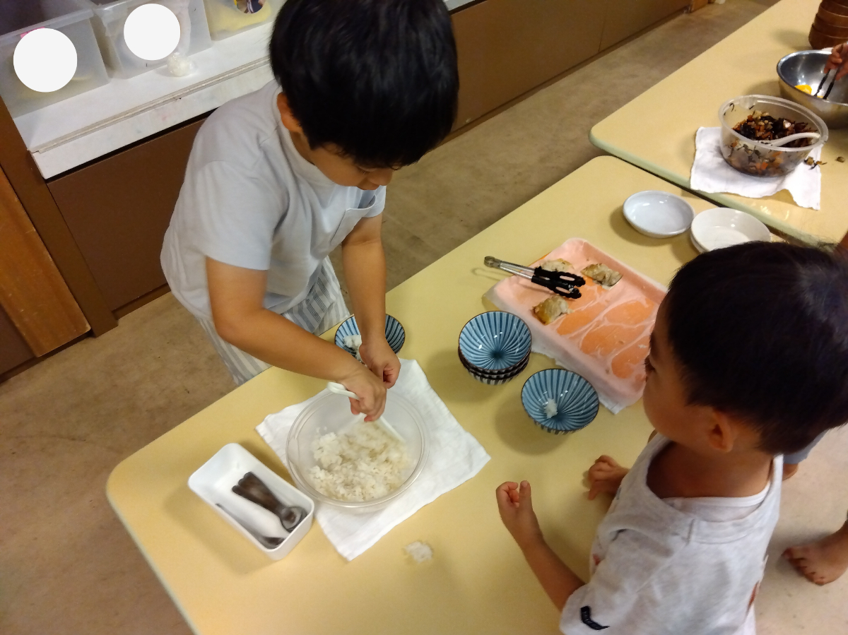 幼児が年下児へごはんをとりわける様子