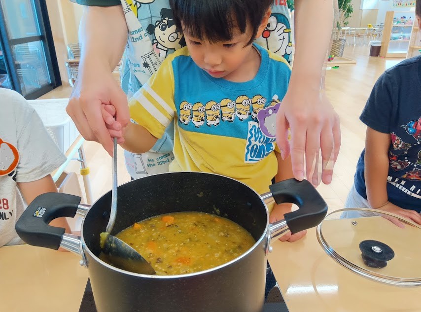 鍋でカレーを煮る子ども