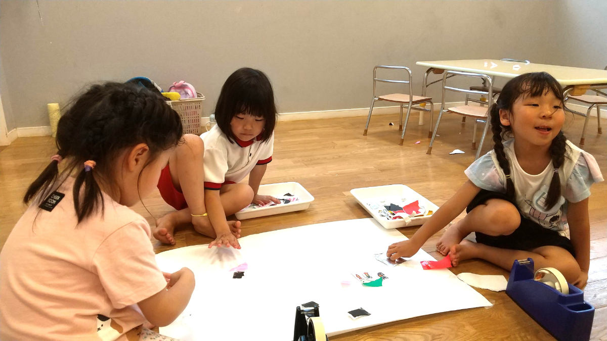 折り紙を張り付けて遊ぶ子どもたち
