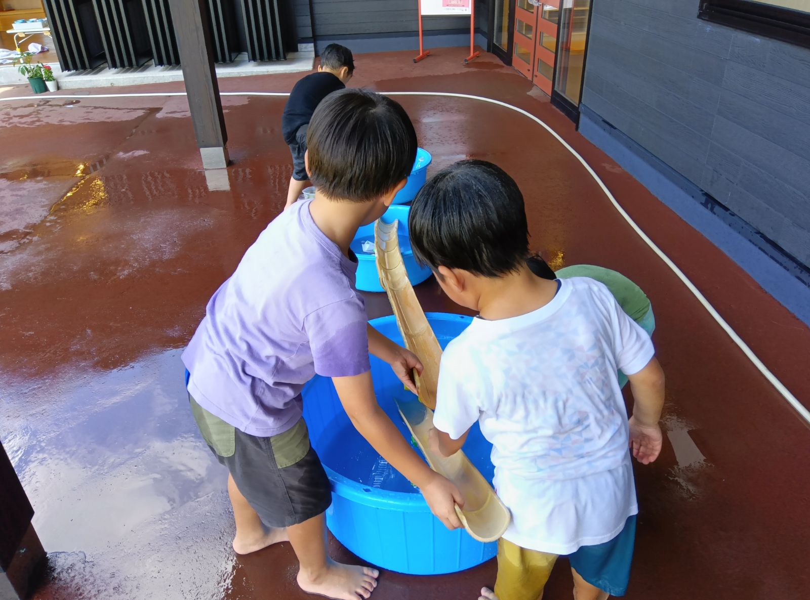 竹で作った水路で遊ぶ子どもたち