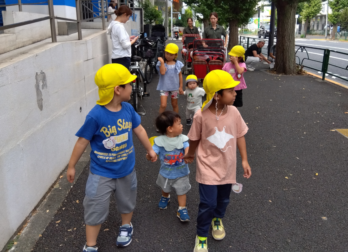 4~5歳児と手を繋いで歩く乳児