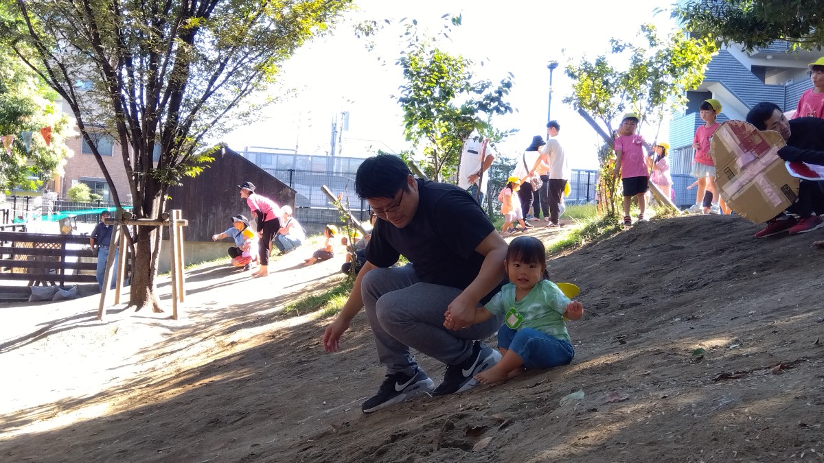 園庭の築山から滑り降りる親子