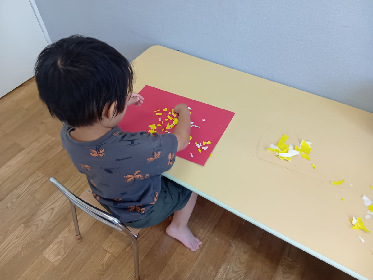 ちぎった色紙を画用紙に並べる子ども