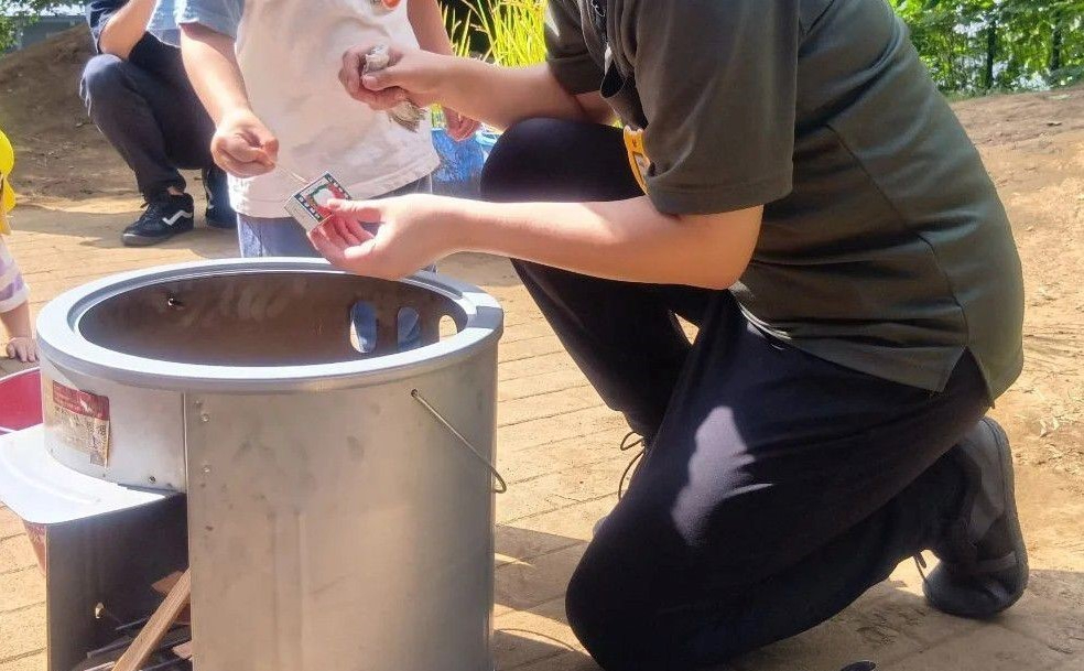 スタッフと一緒にマッチで火をつける子ども