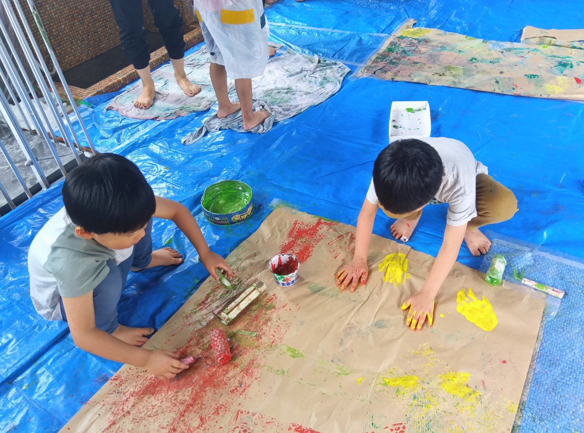 段ボールに絵の具で色を塗る子どもたち