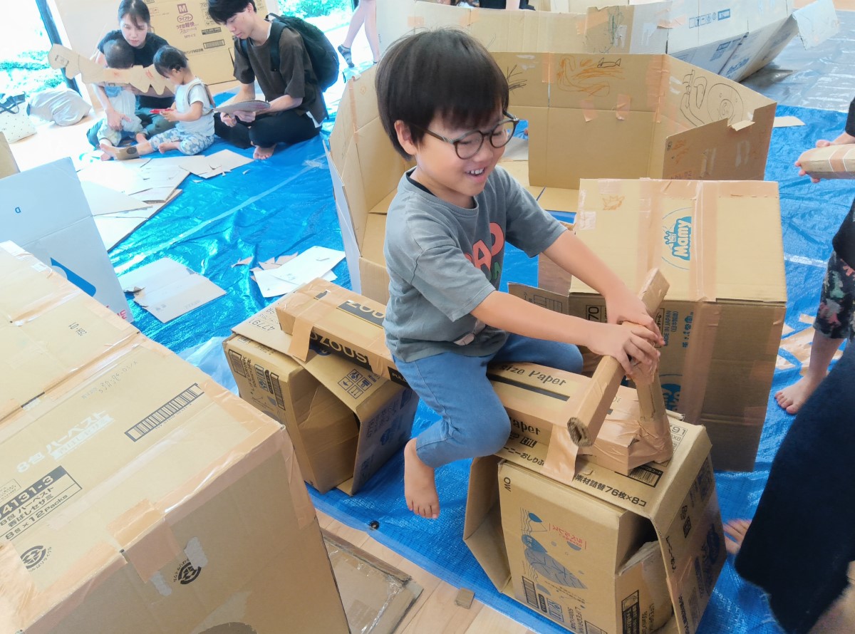 段ボールで作ったバイクに乗る子ども